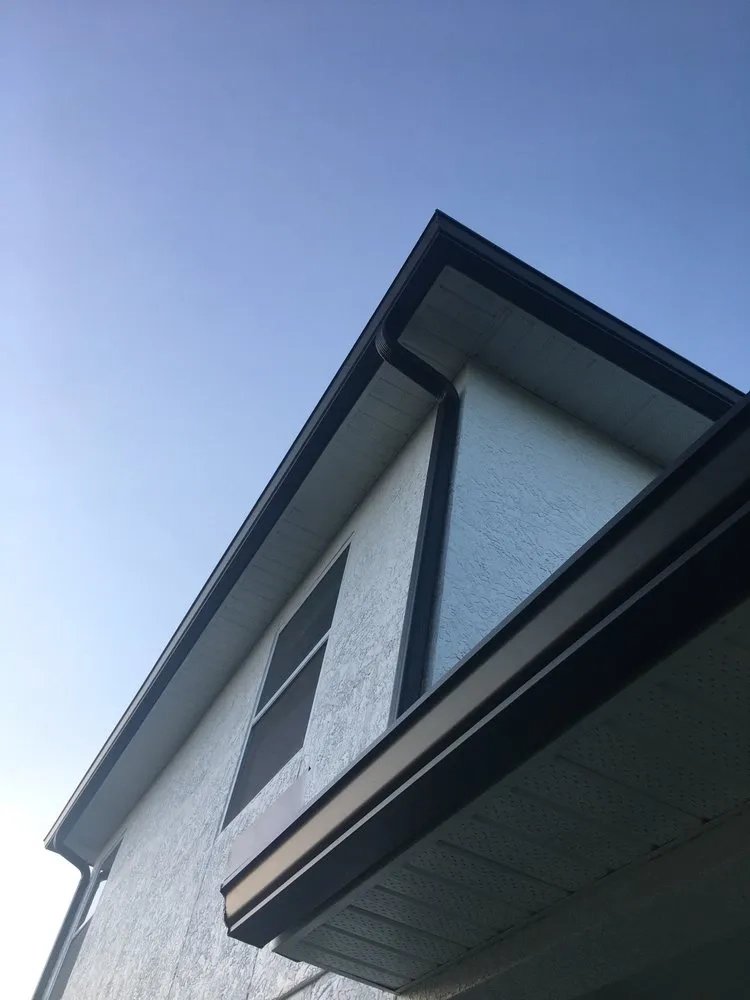 Black seamless gutter and downspout installation on two-story residential home