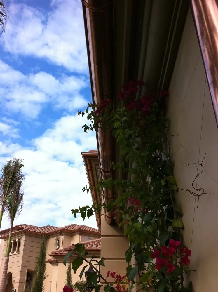 Copper gutter installation along luxury Mediterranean-style home roofline