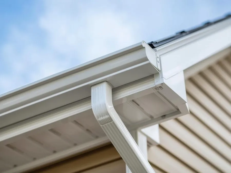 Clean white seamless gutter and downspout installed on modern residential home exterior