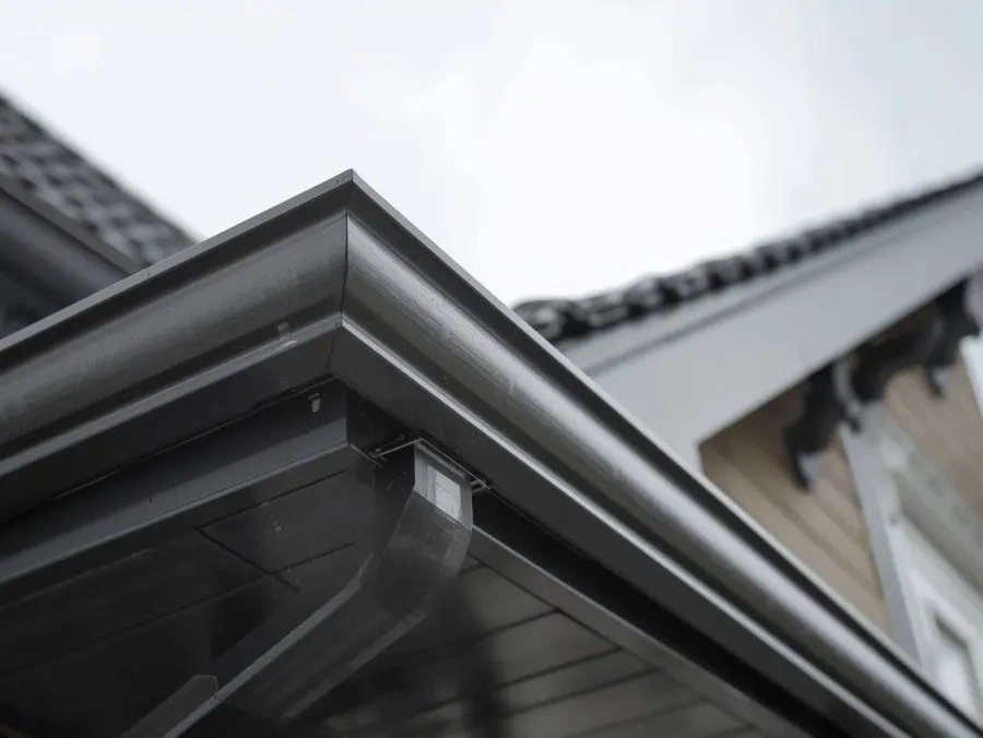 Black seamless gutter corner detail installed on residential roof with durable modern finish