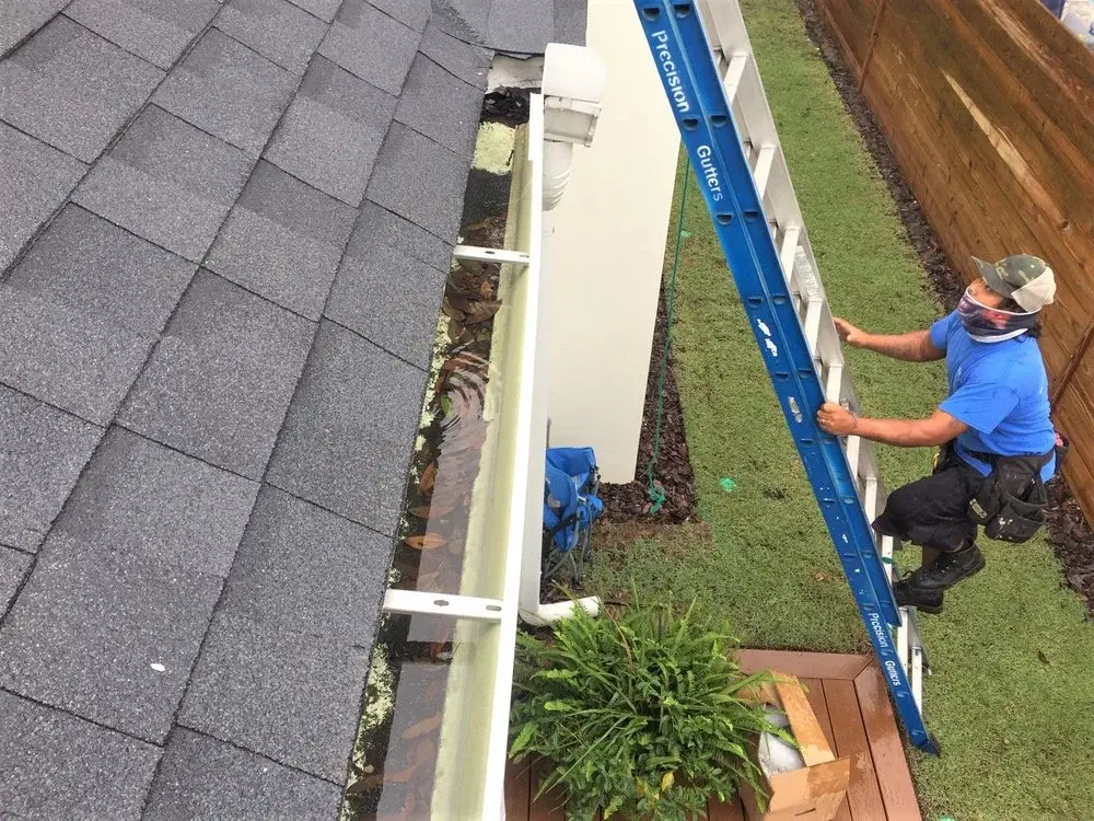 Precision Gutters technician cleaning and repairing residential gutter system to improve drainage performance