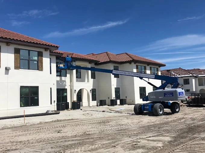 Precision Gutters completing commercial seamless gutter installation on large Florida residential development