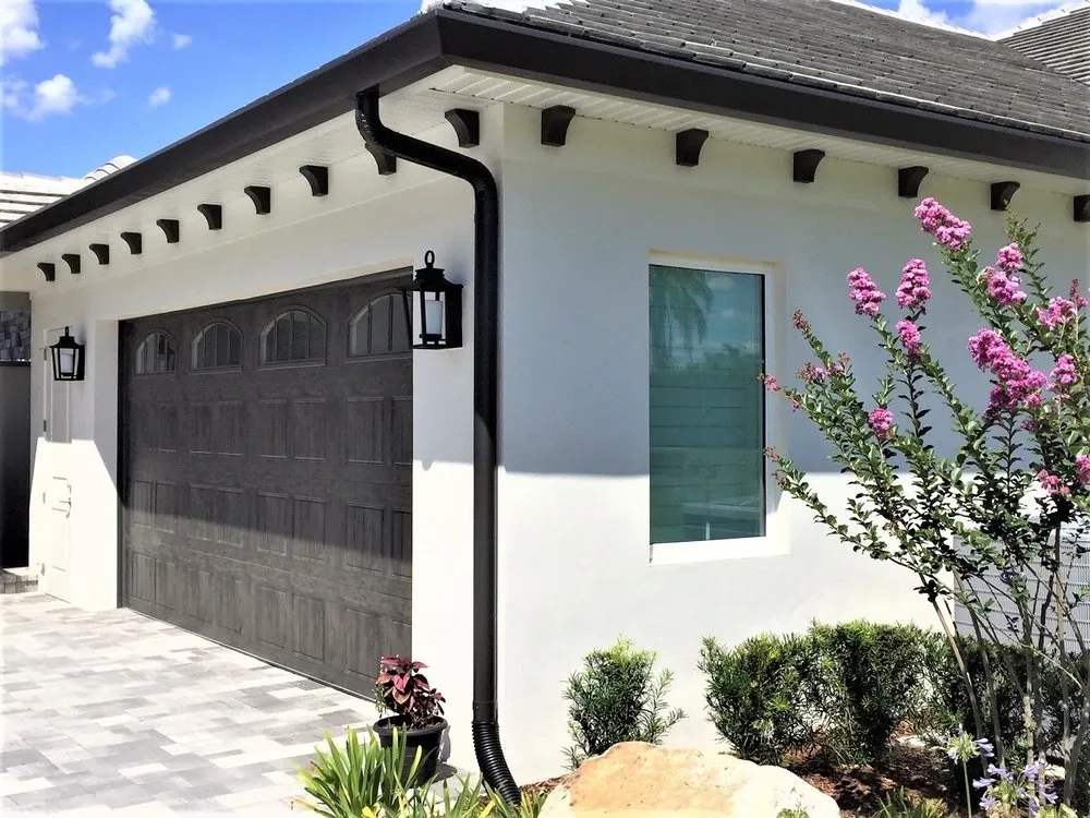 Black seamless gutter and downspout installation on modern white home