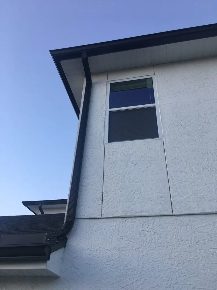 Black downspout installation on two-story residential home exterior