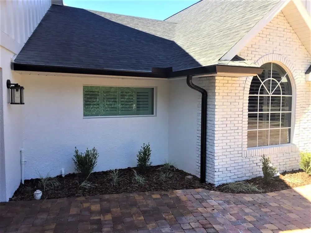 Black seamless aluminum gutter system installed on brick home exterior