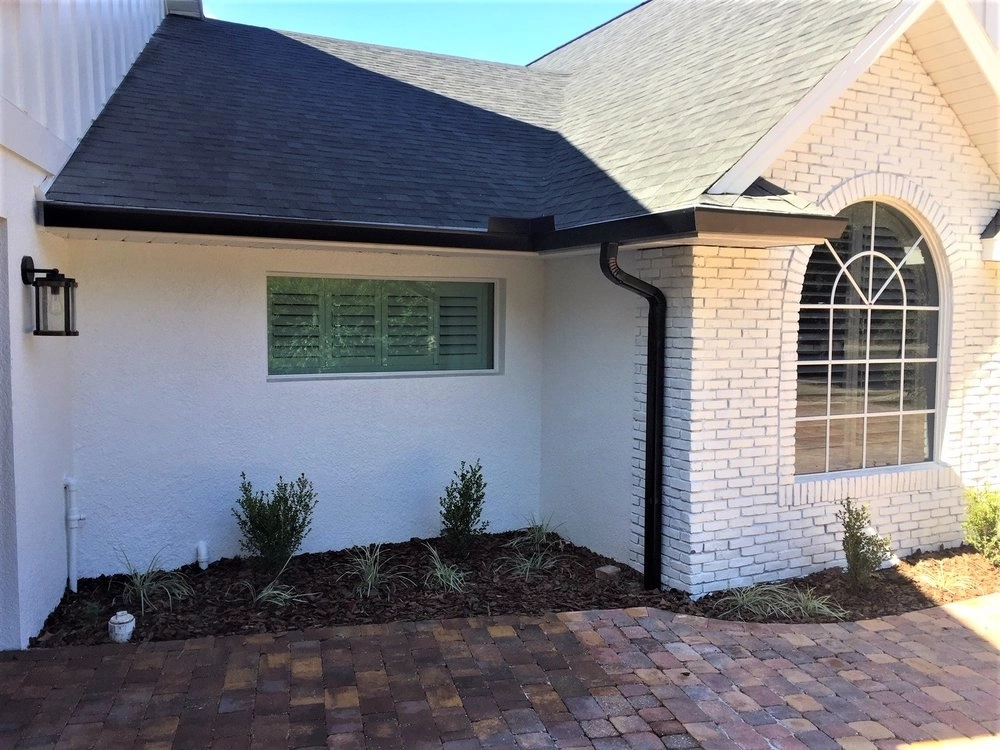 Contemporary Florida home with black seamless gutter system designed for efficient rainwater drainage