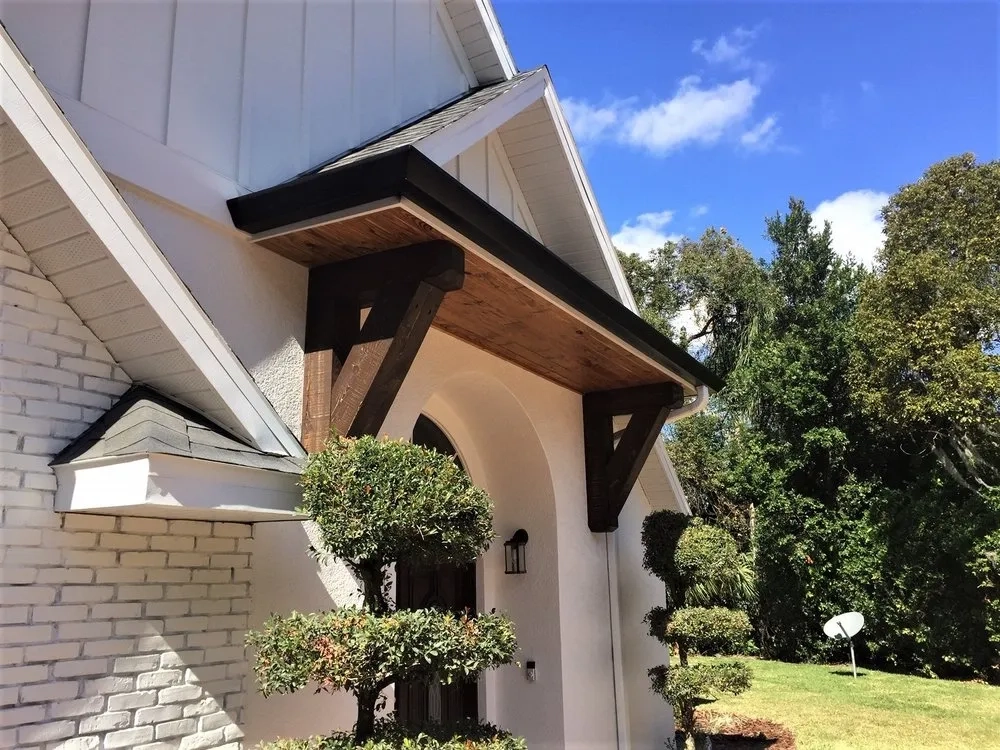 Black seamless gutter installation on custom residential entryway