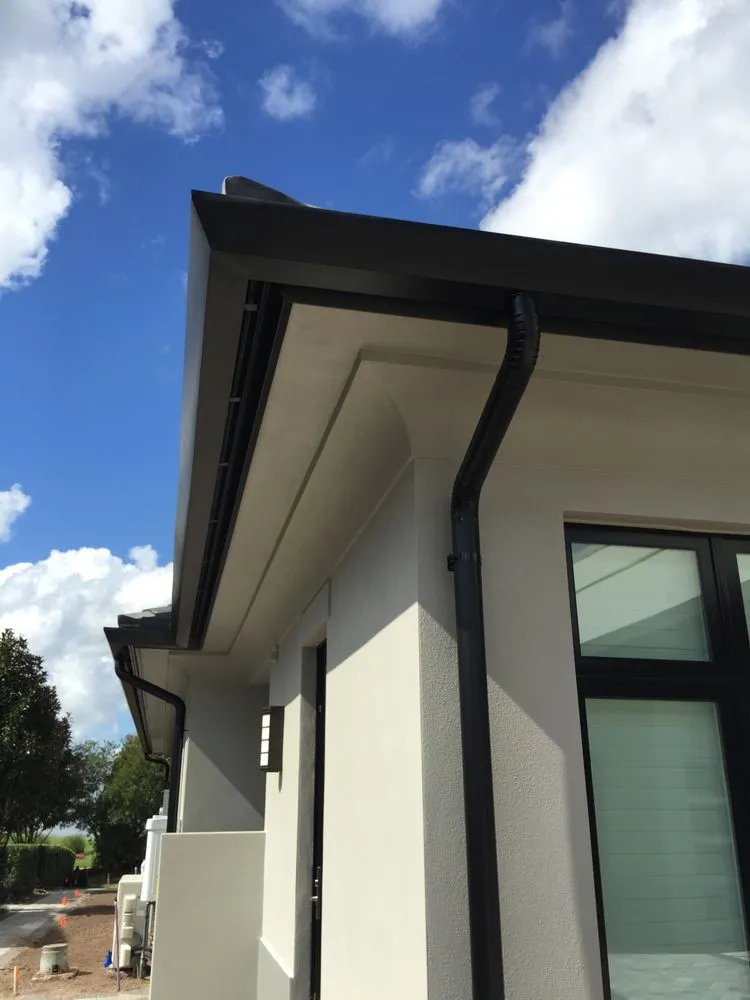 Contemporary Florida home with black seamless gutter system designed for efficient rainwater drainage