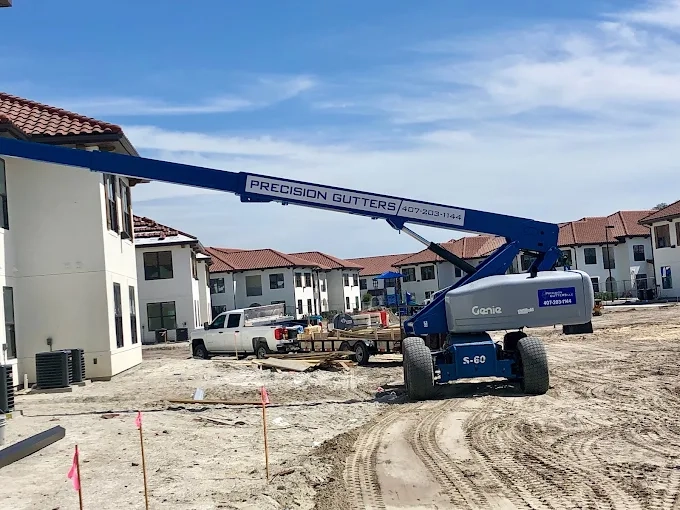Precision Gutters FL aerial lift equipment at a residential construction site, supporting seamless gutter installation on newly built multi-family homes in Florida.