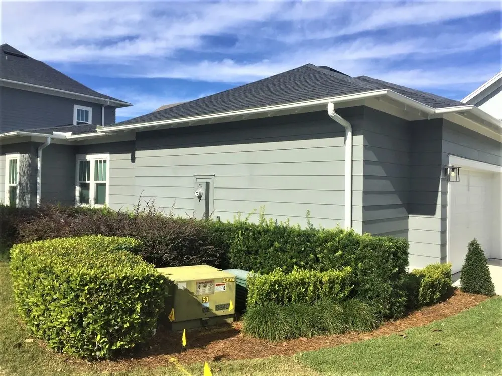 Gray residential home with white aluminum gutter system installed for effective roof drainage
